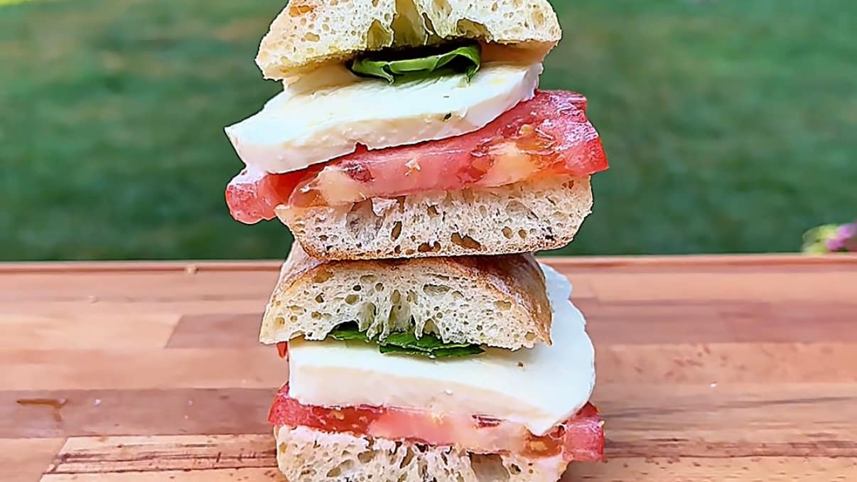 Caprese Panino made with ripe summer tomatoes, fresh mozzarella, basil, and extra virgin olive oil on crusty Italian bread.