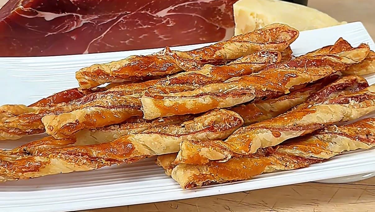 Puff Pastry Grissini layered with Prosciutto di Parma and Parmigiano Reggiano, baked until flaky, crisp, and golden brown.
