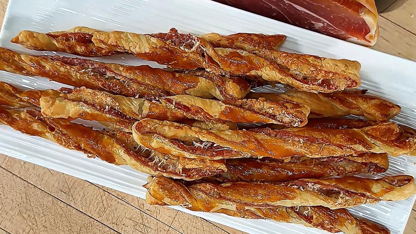 Puff Pastry Grissini layered with Prosciutto di Parma and Parmigiano Reggiano, baked until flaky, crisp, and golden brown.