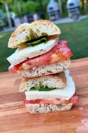 Caprese Panino made with ripe summer tomatoes, fresh mozzarella, basil, and extra virgin olive oil on crusty Italian bread.