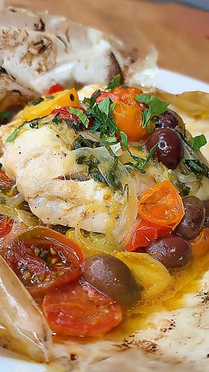 red snapper baked in parchment paper with onion, olives & tomatoes
