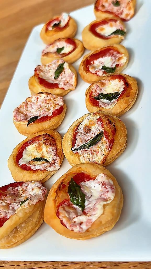 Pizzette di Sfoglia topped with tomato sauce, mozzarella, basil, and flaky golden puff pastry.