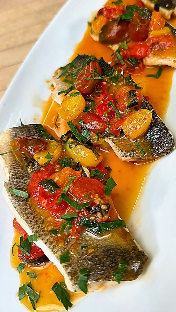 Branzino all’Acqua Pazza with cherry tomatoes, garlic, olive oil, and fresh herbs simmered in a light Mediterranean broth.