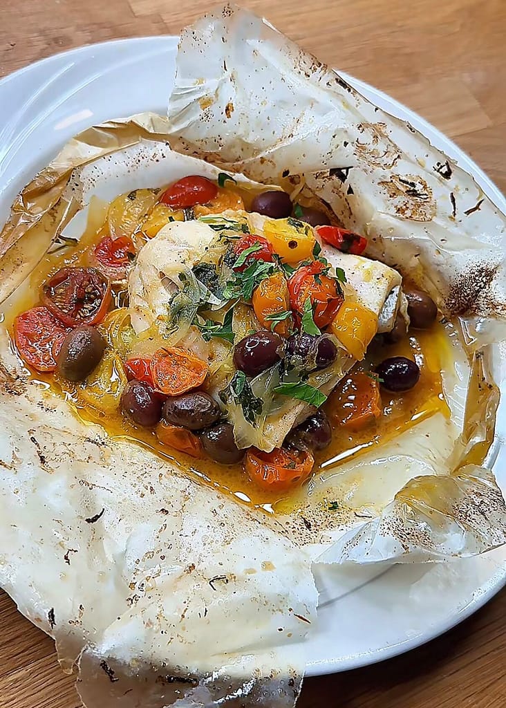 red snapper baked in parchment paper with onion, olives & tomatoes