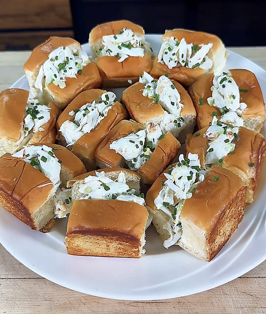 Mini Crab Rolls filled with fresh lump crabmeat, lemon, chives, and celery served on buttery toasted rolls.